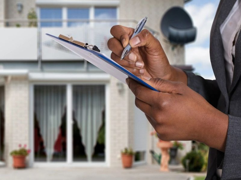 Person Filling Document In Front Of House