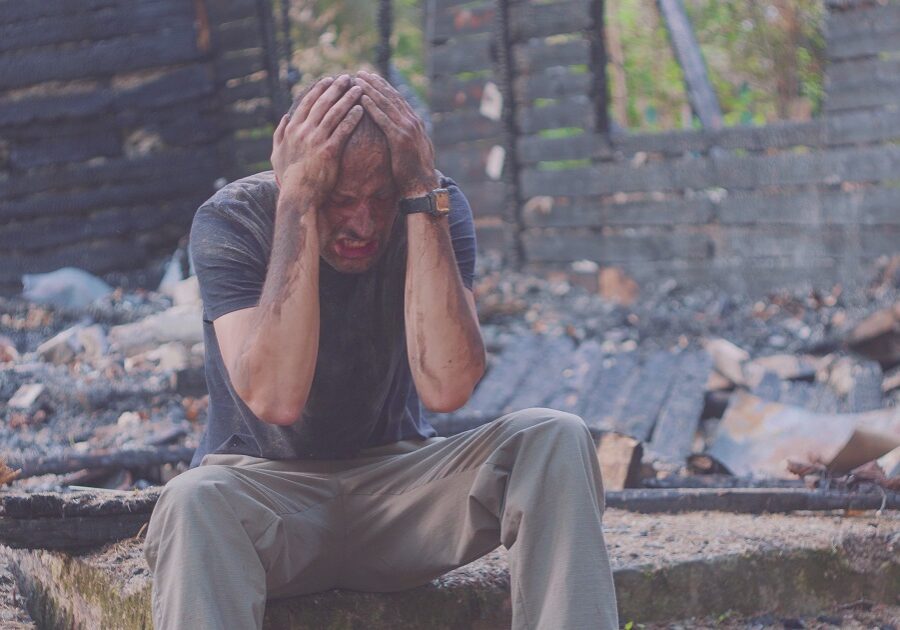 A Man Holding Head Sitting on a Debris Site